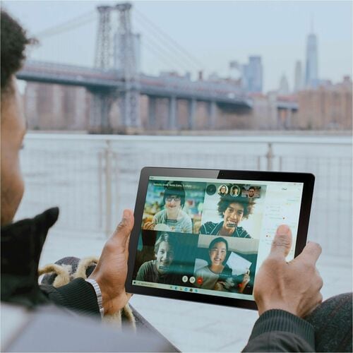 Person using a tablet with a video call interface in front of a bridge and cityscape