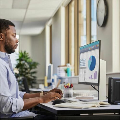 Man working at a desk with a computer displaying graphs in an office setting.