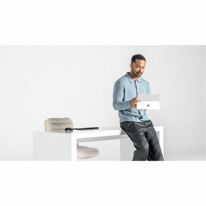Man sitting on a modern white chair holding a laptop with a minimalistic background