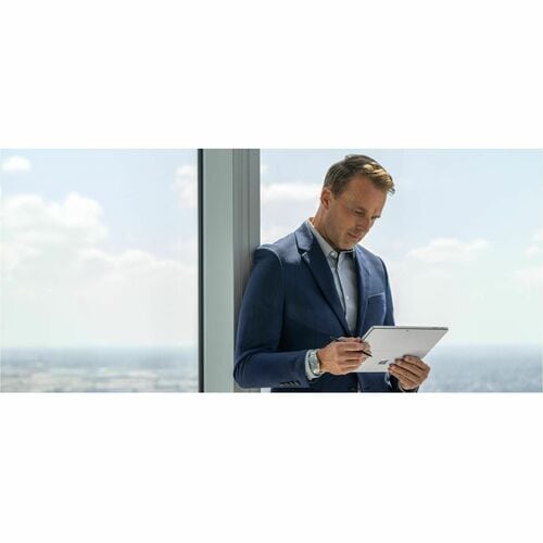 Man in a suit using a tablet by a window with a view of clouds.
