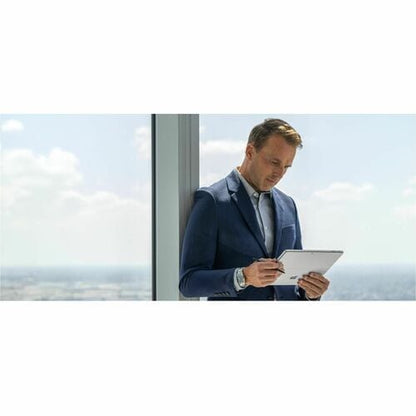 Man in a suit using a tablet by a window with a view of clouds.