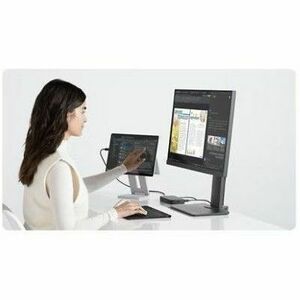 Person working at a desk with two computer monitors on a white background