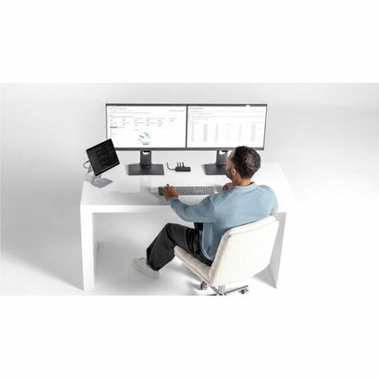 Person sitting at a modern desk with multiple computer monitors and devices.