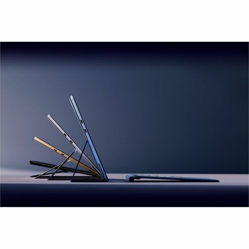 Three laptop computers stacked on a dark surface with a gradient background