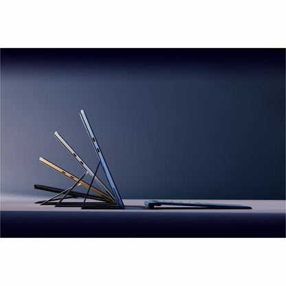 Three laptop computers stacked on a dark surface with a gradient background