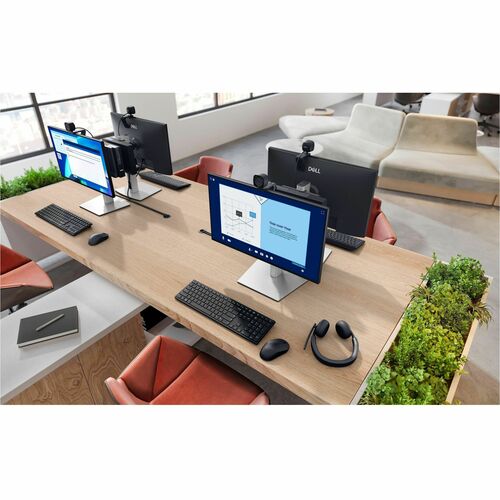 Modern office desk setup with multiple computer monitors, keyboards, and a chair.