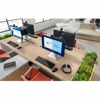 Modern office desk setup with multiple computer monitors, keyboards, and a chair.